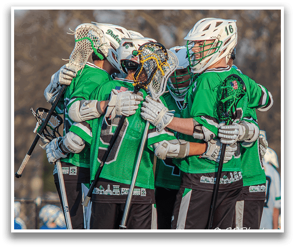 A group of men wearing green shirts and black shorts hugging each other. Description generated by AI