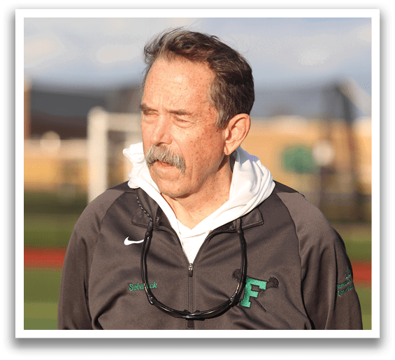 A man wearing a gray jacket with a green F on it. Description generated by AI