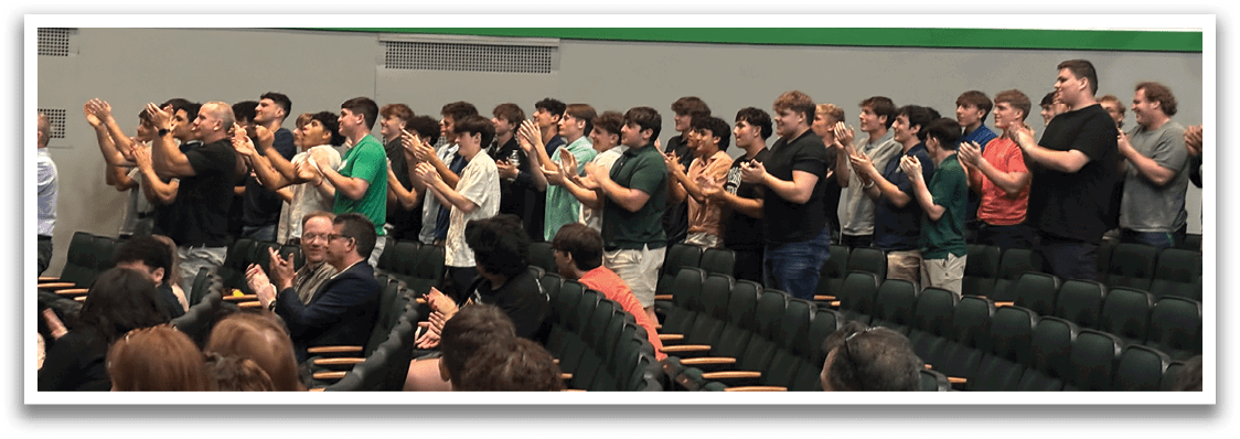 A group of people clapping in a room. Description generated by AI