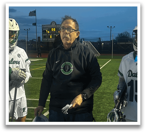 A man wearing a black jacket and glasses is standing on a field. Description generated by AI