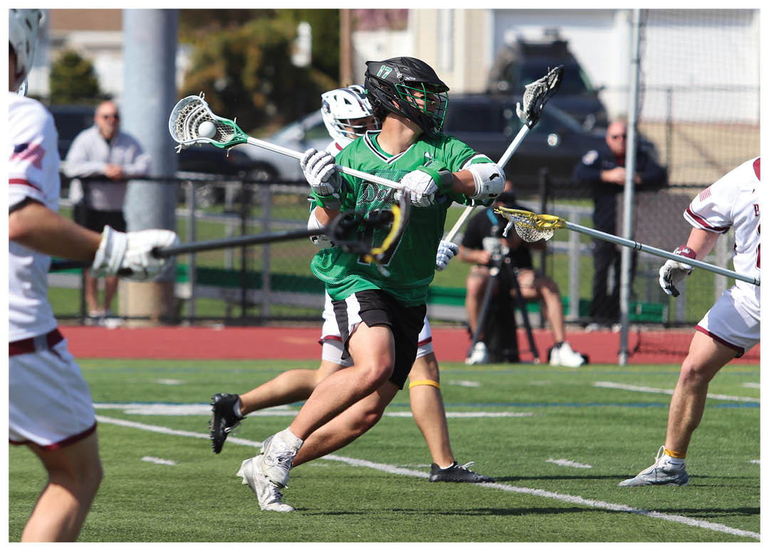 A man in a green shirt is running with a lacrosse stick. Description generated by AI