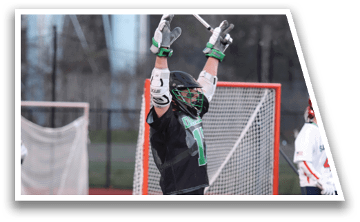 A man in a black shirt and green shorts is holding a lacrosse stick. Description generated by AI