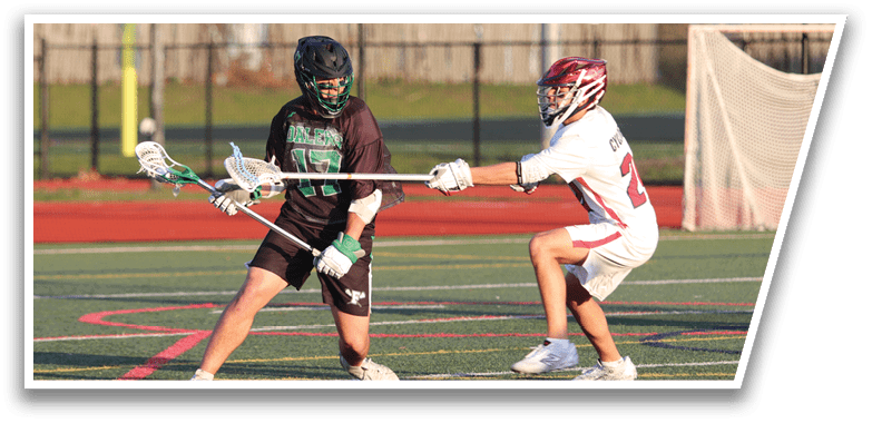 A man in a black shirt and green shorts is holding a lacrosse stick. Description generated by AI