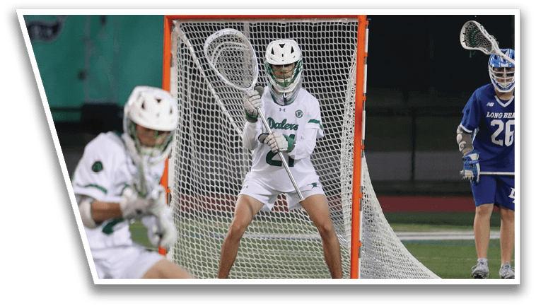 A man is holding a lacrosse stick in front of a net. Description generated by AI