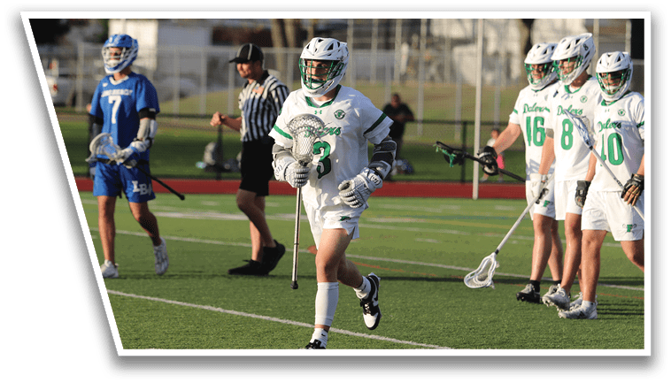 A group of people playing lacrosse on a field. Description generated by AI