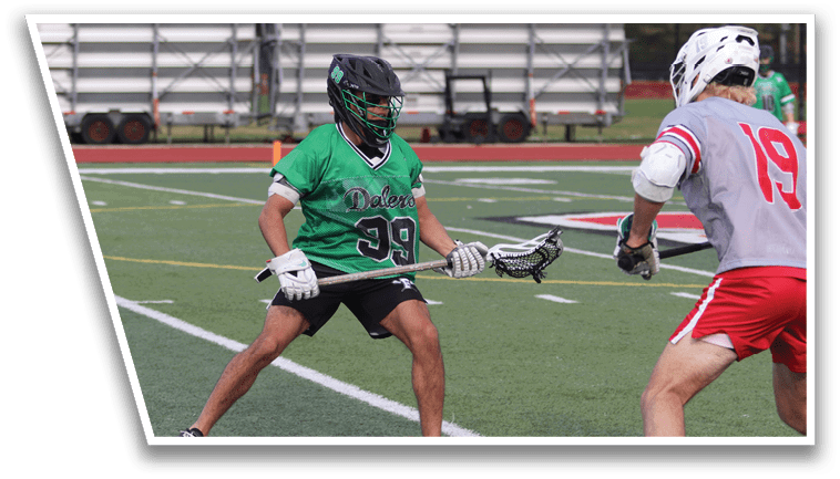 A man wearing a green jersey is holding a stick. Description generated by AI