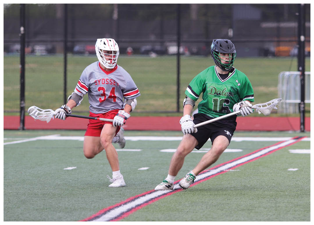 Two people playing lacrosse on a field. Description generated by AI