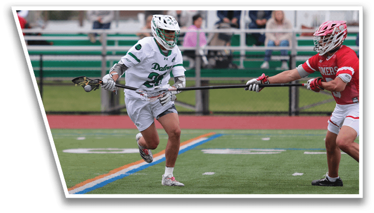 A man in a green and white uniform is running on a field with a lacrosse stick. Description generated by AI