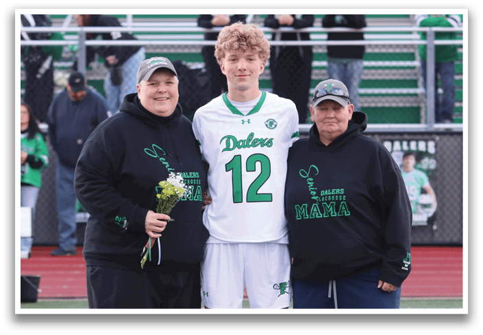 A man wearing a green and white jersey stands between two people. Description generated by AI