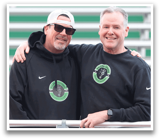 Two men wearing black sweatshirts with green logos. Description generated by AI