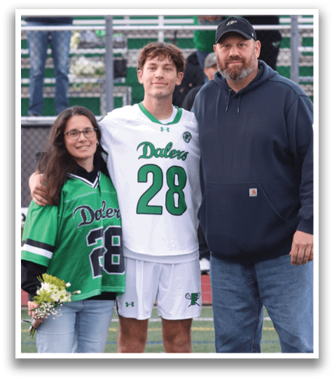 A man and woman standing on a football field with a man in a jersey with the number 26. Description generated by AI
