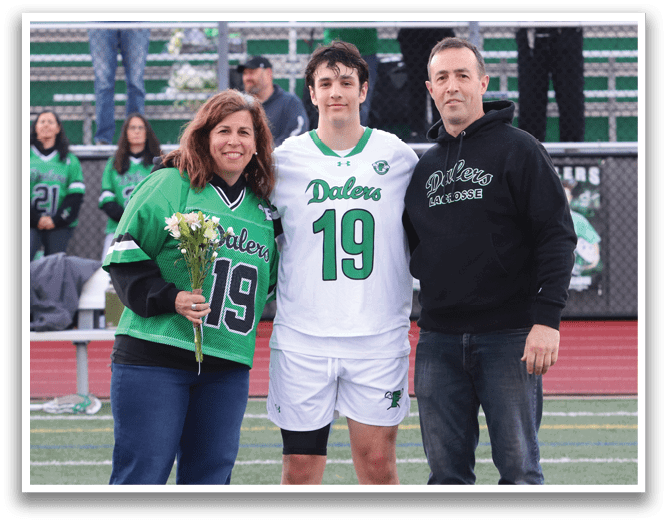 A man and woman stand on a football field with a man in a green jersey. Description generated by AI