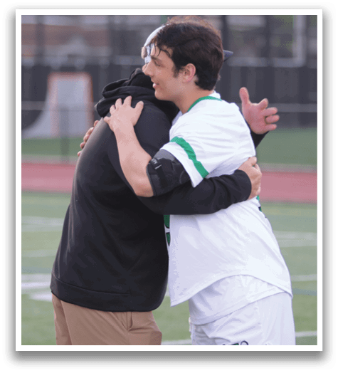 Two men hugging each other on a field. Description generated by AI