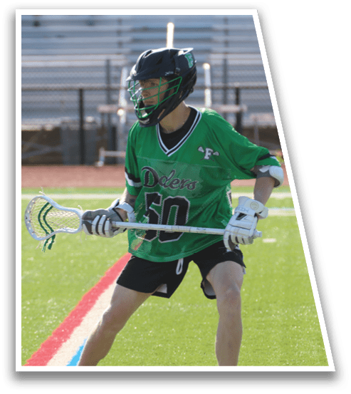 A man wearing a green shirt and black shorts is holding a lacrosse stick. Description generated by AI