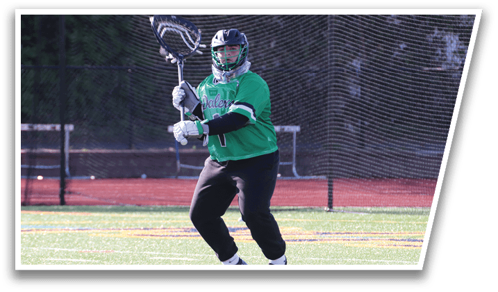 A person wearing a green shirt and black pants holding a lacrosse stick. Description generated by AI