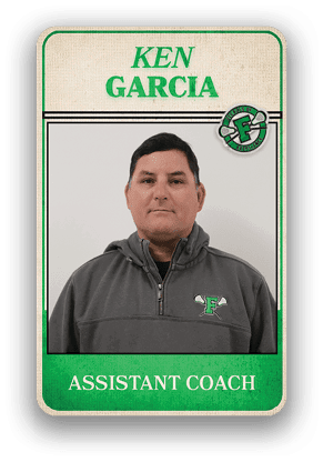 Person wearing a gray quarter-zip pullover with a green and white logo standing in front of a sign that reads Ken Garcia Assistant Coach. Description generated by AI