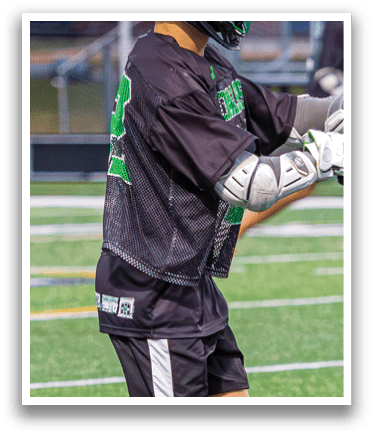A man in a black shirt and white pants is holding a lacrosse stick on a field. AI generated content