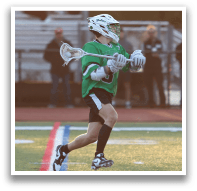 A man in a green shirt and black shorts is running with a lacrosse stick. Description generated by AI