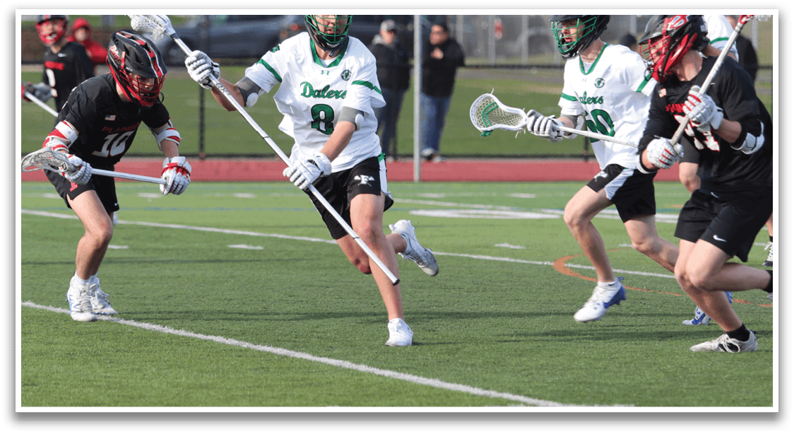 A group of men playing lacrosse on a field. Description generated by AI