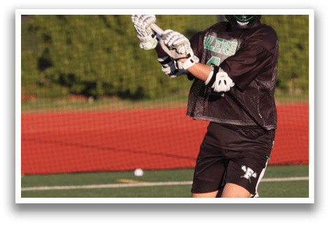 A man holding a lacrosse stick on a field. Description generated by AI