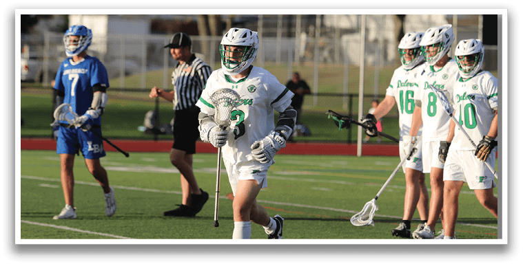 A group of people playing lacrosse on a field. Description generated by AI