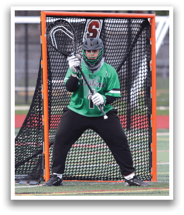 A man in a green shirt is playing lacrosse. Description generated by AI