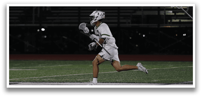 A man running on a field with a white and green jersey. Description generated by AI
