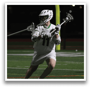 A man in a white uniform is holding a lacrosse stick. Description generated by AI