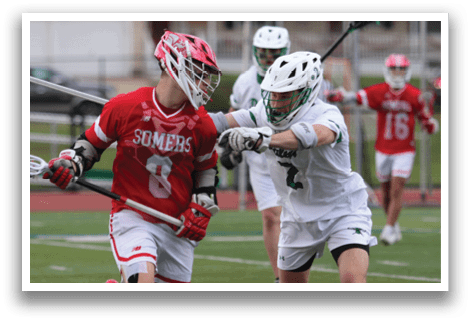 Two men playing lacrosse on a field. Description generated by AI
