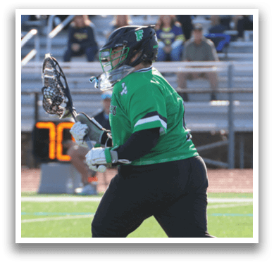 A man in a green shirt and black pants is running with a lacrosse stick. Description generated by AI