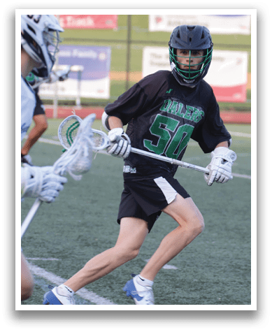 A man wearing a black shirt and white pants is holding a lacrosse stick. Description generated by AI