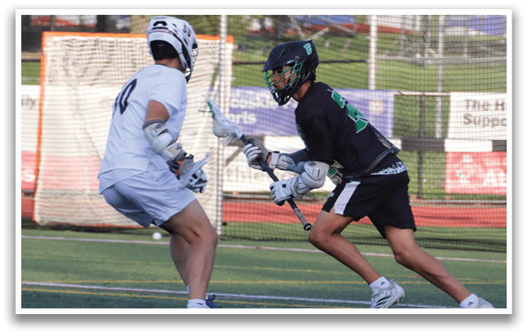 Two men playing lacrosse on a field. Description generated by AI
