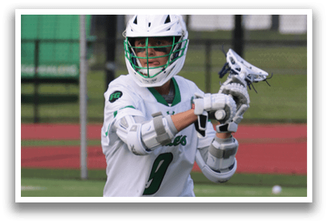 Two men playing lacrosse on a field. Description generated by AI