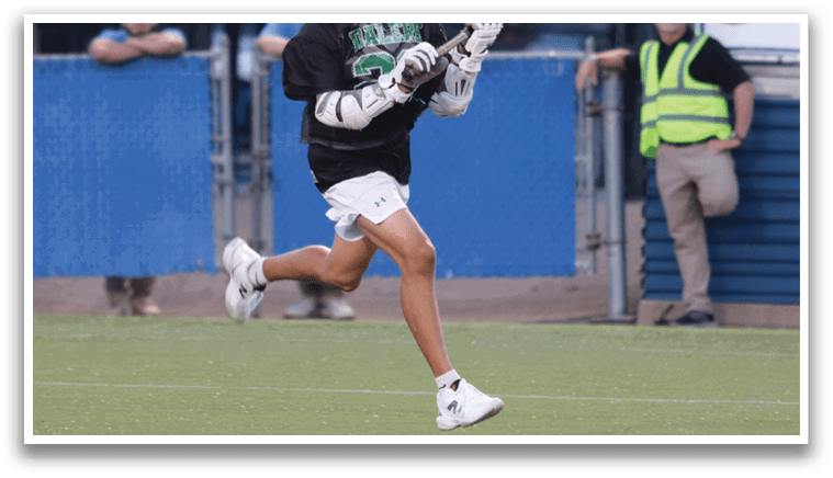 Two men playing lacrosse on a field. Description generated by AI