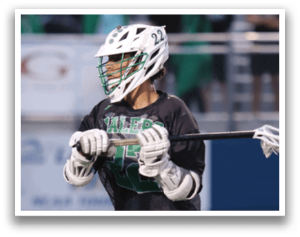 A man wearing a green and white uniform is playing lacrosse. Description generated by AI