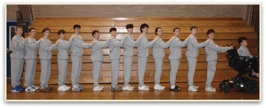 A group of young men are standing in a gym, wearing grey sweatshirts and white shoes. They are lined up in a row, with some of them holding hands with their neighbors. AI generated content