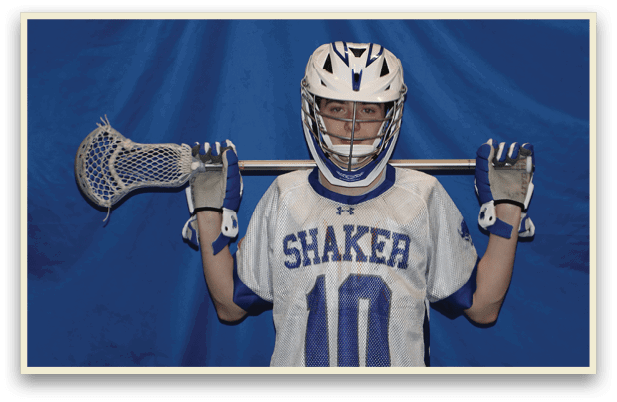 A young man wearing a Shaker jersey holds a lacrosse stick. AI generated content