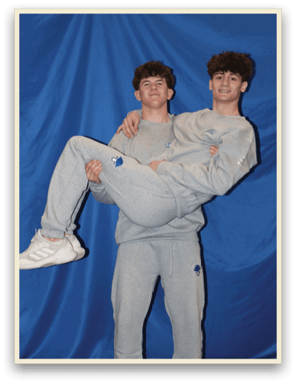 Two young men are posing for a picture, one of them is holding the other's legs. AI generated content