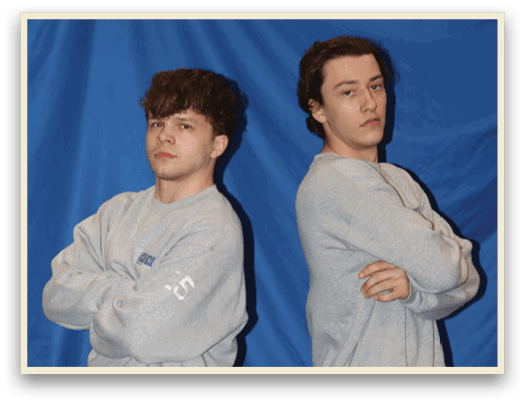 Two young men pose for a picture in matching grey sweatsuits. AI generated content