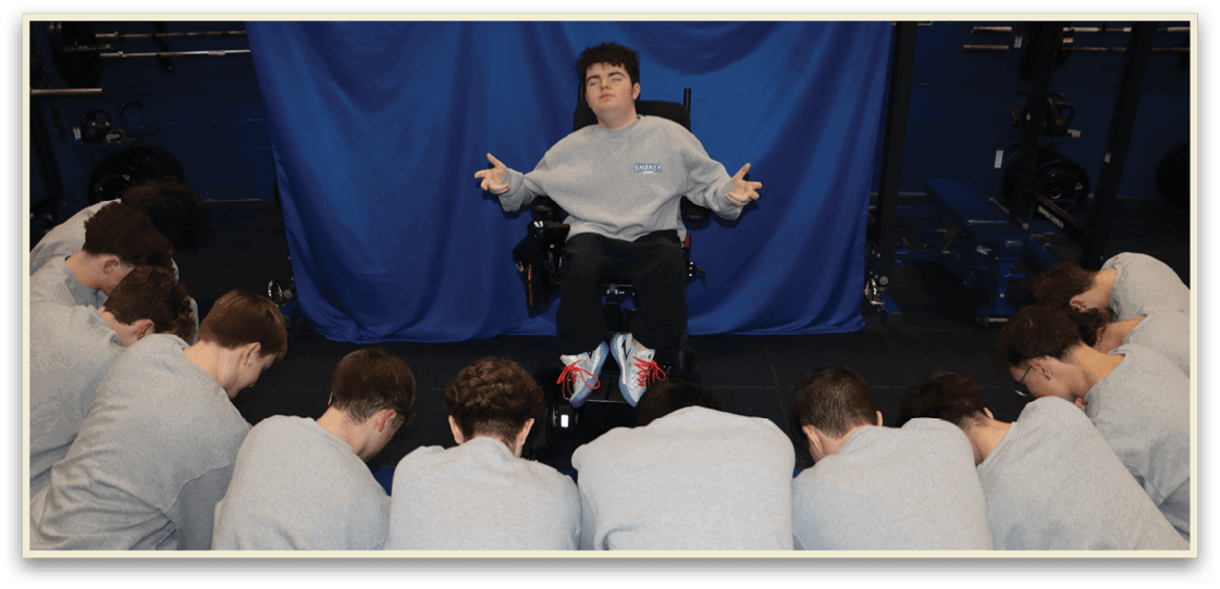 A man in a wheelchair is surrounded by a group of people who are kneeling in front of him. AI generated content