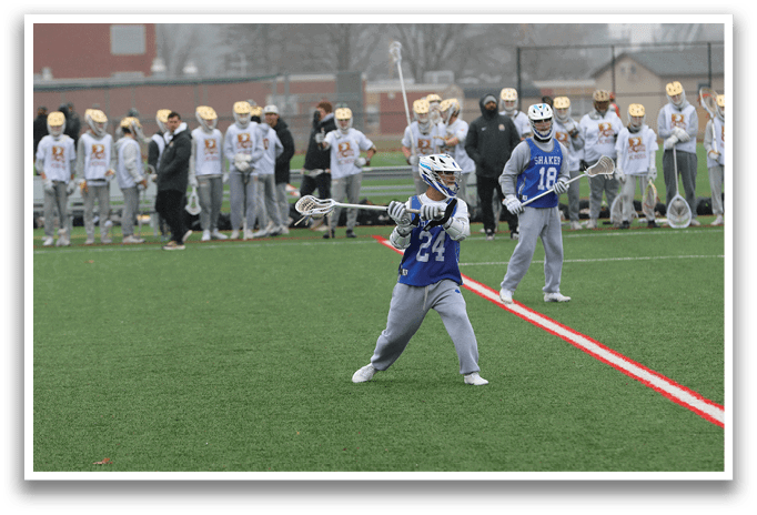 A man in a blue shirt and grey pants is holding a lacrosse stick and preparing to throw the ball. AI generated content