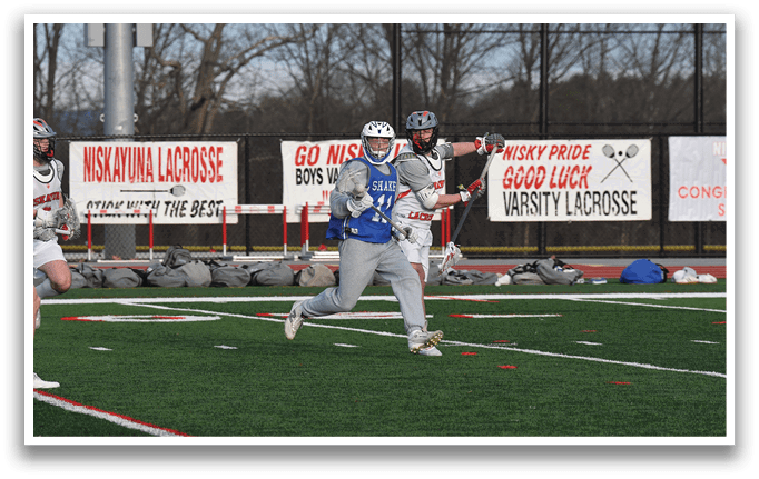 Two men playing lacrosse on a field. One man is holding a stick and the other is running. AI generated content