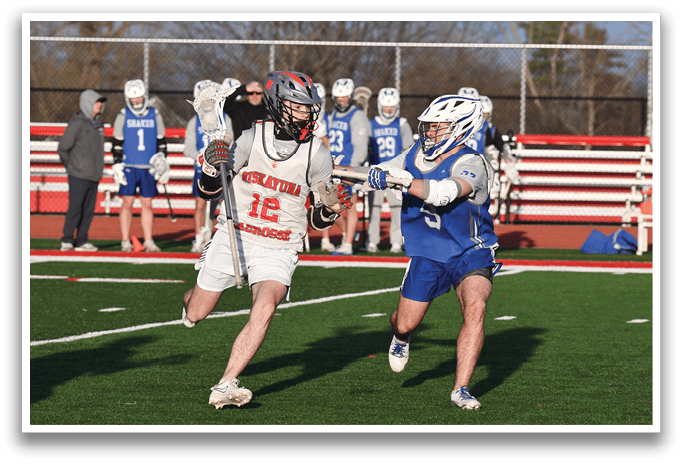 Two lacrosse players are running on a field, one with a blue shirt and the other with a red shirt. They are both holding lacrosse sticks. AI generated content