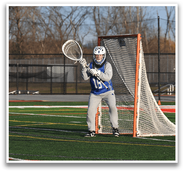 A person wearing a blue and white uniform is standing in front of a net, holding a lacrosse stick. AI generated content