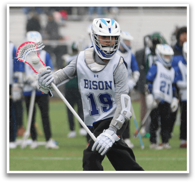 A person wearing a Bison jersey is holding a lacrosse stick and walking on a field. AI generated content