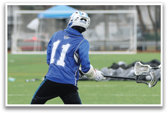 A man in a blue and white jersey is playing lacrosse on a field. AI generated content