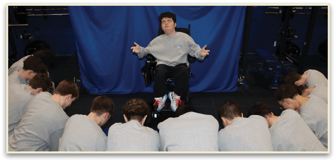 A man in a wheelchair is surrounded by a group of people who are kneeling in front of him. AI generated content
