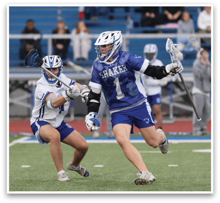 Two men playing lacrosse on a field. One player is running with a stick, while the other is trying to block him. AI generated content