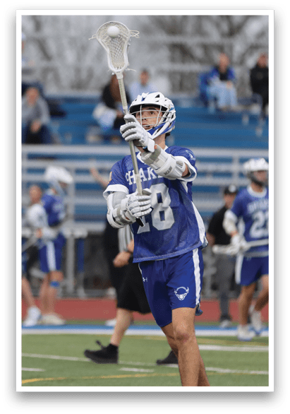 A man wearing a blue and white uniform holds a lacrosse stick in the air. AI generated content