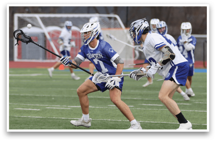 Two lacrosse players are running on a field, one with a blue jersey and the other with a white jersey. AI generated content